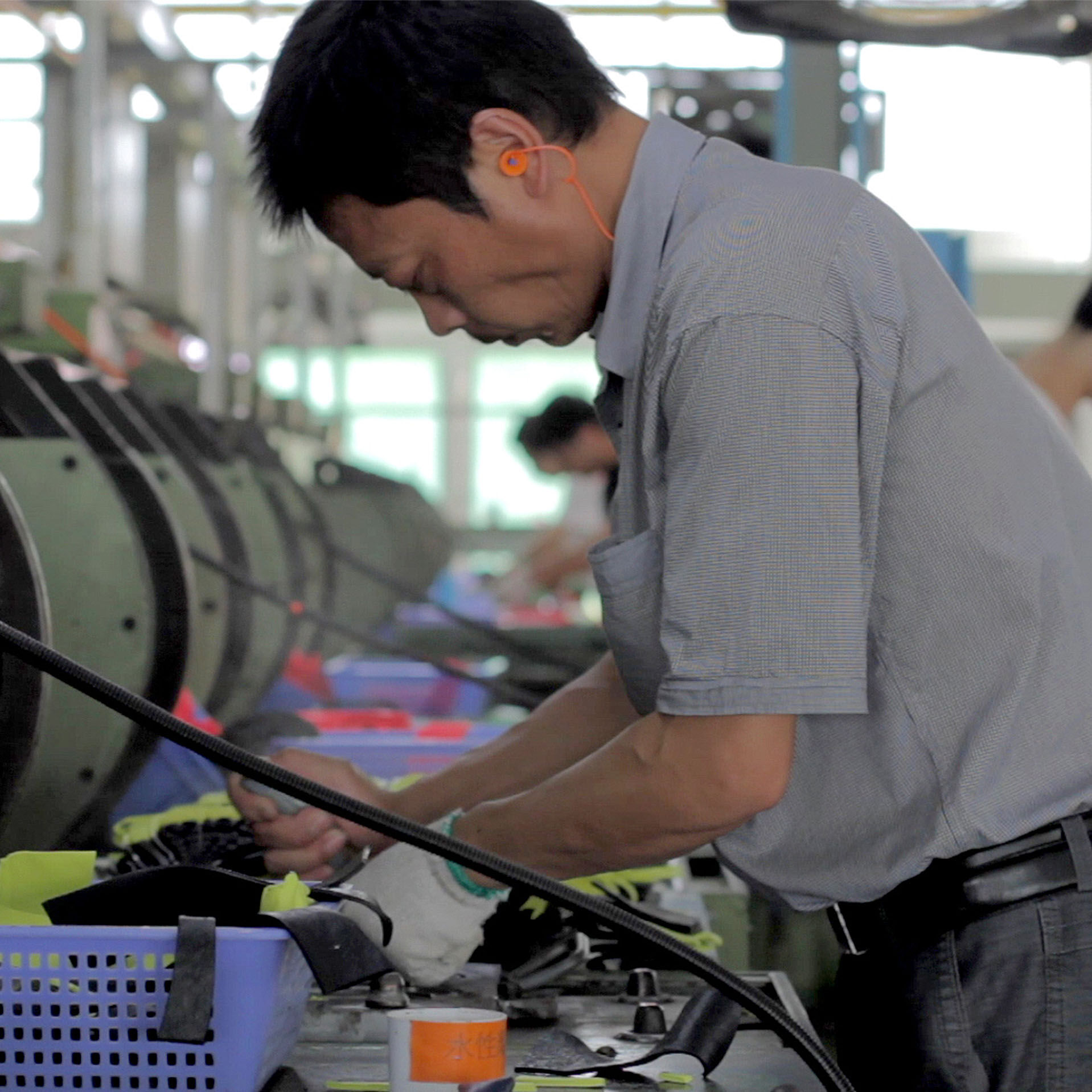 Male factory worker using machine to cut material